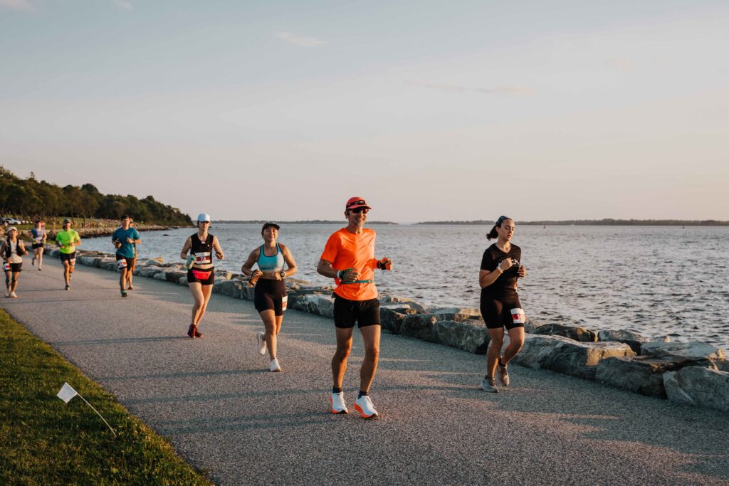 Marathon runners on a sunset-lit coastal path