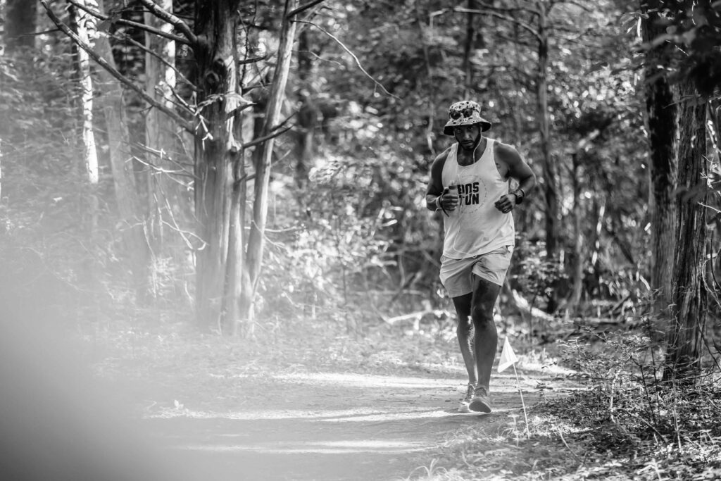 Focused runner trekking through a lush forest trail during the Anchor Down Ultra Marathon event.